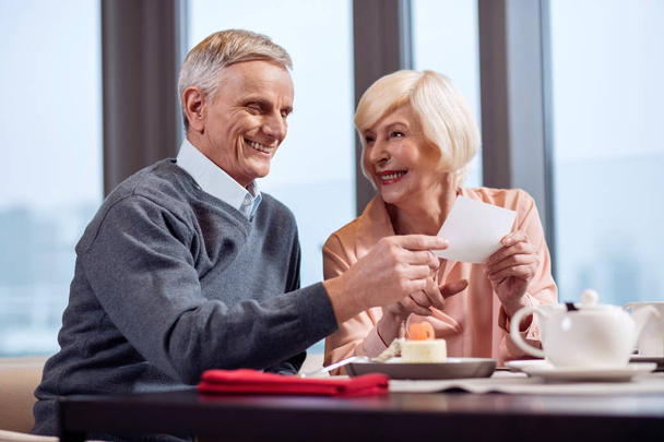 Cheerful mature couple reading card - Foto, afbeelding
