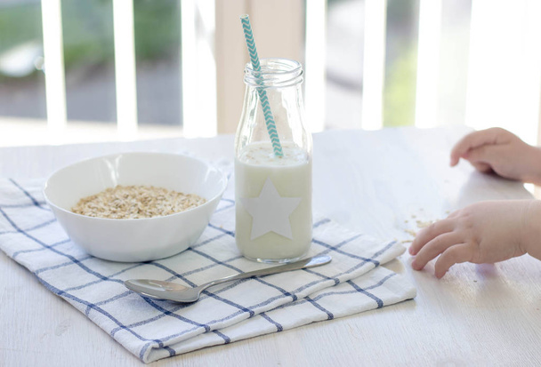 Bijgesneden foto van een kind zijn ontbijt eten. Gezonde voeding. Muesli, melk. Gezondheid. Kinder-handen en voedsel. Gezellige. - Foto, afbeelding
