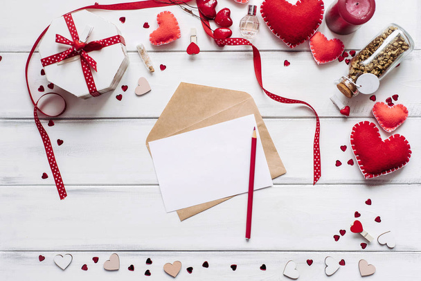 Composición decorativa con corazones hechos a mano, trozo de papel, botella con piezas de oro y carta sobre tablones de madera de fondo para el día de San Valentín
. - Foto, Imagen
