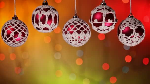 Primer plano de cinco adornos rojos de Navidad colgando sobre un fondo borroso de luces parpadeantes
 - Imágenes, Vídeo