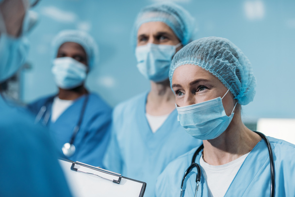 multicultural surgeons looking away in operating room - Photo, image
