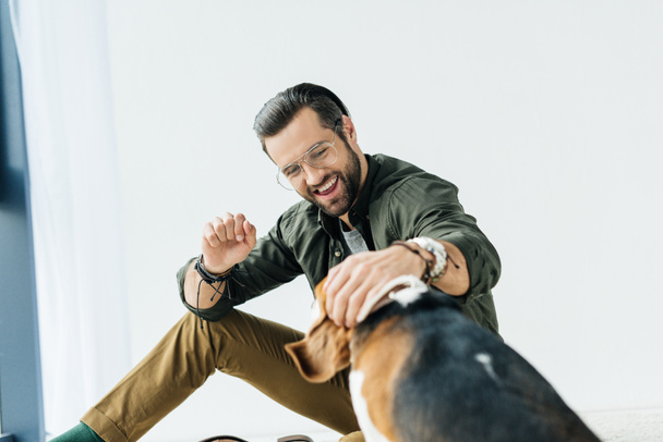 szczęśliwy człowiek siedzi na podłodze i zabawy z psem - Zdjęcie, obraz