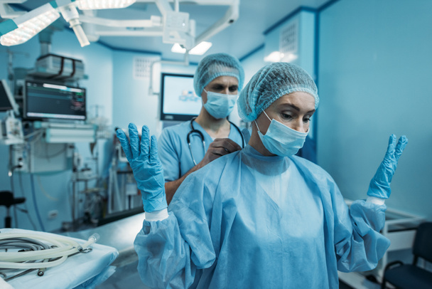 médico ayudando a usar uniforme quirúrgico para el cirujano
 - Foto, imagen