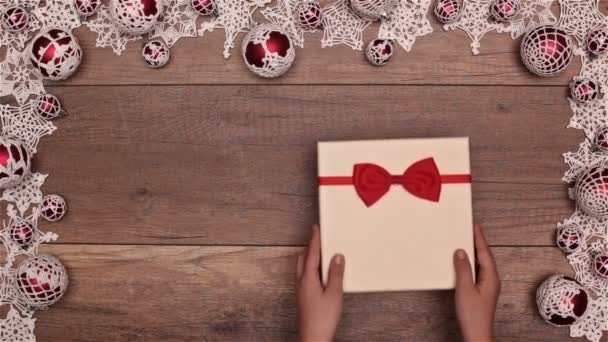 pohled shora rukou otevírání vánoční dárek sezónní rámečku na dřevěný stůl - Záběry, video
