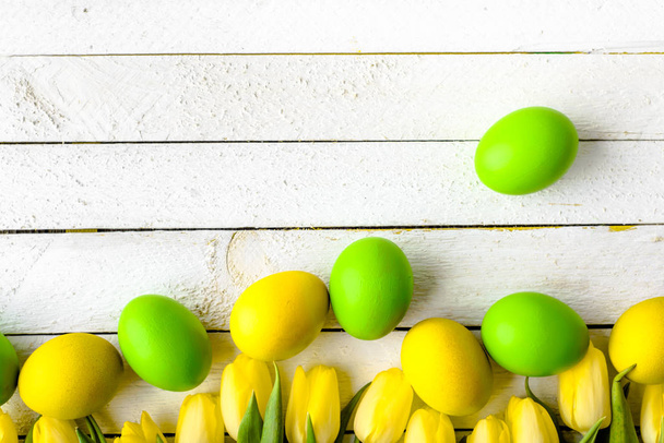 Happy easter eggs and tulips on wooden table, festive decoration - Photo, image
