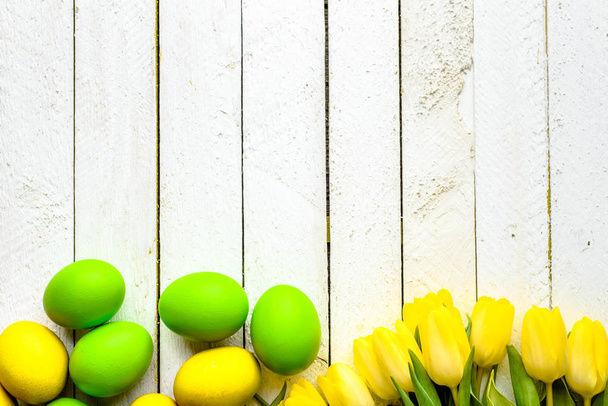 Wooden background with spring easter eggs and tulips on table, top view - Foto, Bild