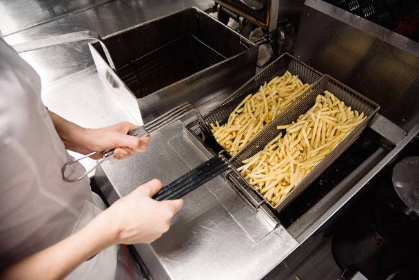 Διαδικασία της λήψης τηγανιτής πατάτας στην κουζίνα. Εστιατόριο, καφενείο ή πιτσαρία κουζίνα - Φωτογραφία, εικόνα