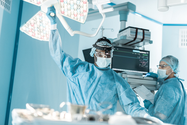 афроамериканський лікар встановлює хірургічне світло
 - Фото, зображення