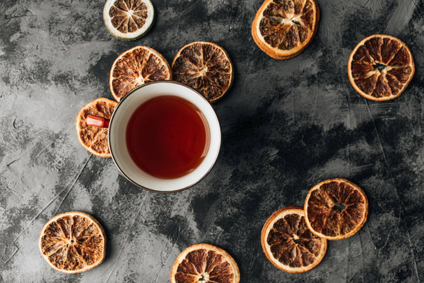 rodajas de naranjas secas y taza de té en la mesa de piedra oscura
 - Foto, Imagen