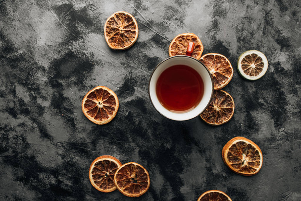 rodajas de naranjas secas y taza de té en la mesa de piedra oscura
 - Foto, Imagen