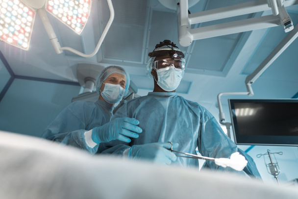 κάτω όψη πολυπολιτισμική χειρουργών στη χειρουργική επέμβαση - Φωτογραφία, εικόνα