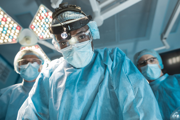 vista inferior del cirujano afroamericano mirando a la cámara
 - Foto, Imagen