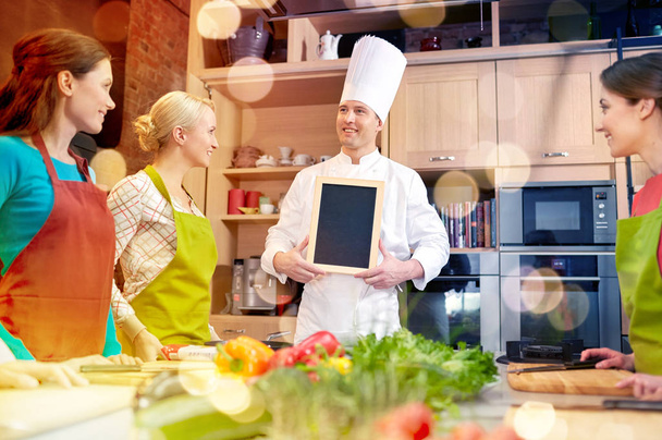 happy women and chef cook with menu in kitchen - Zdjęcie, obraz