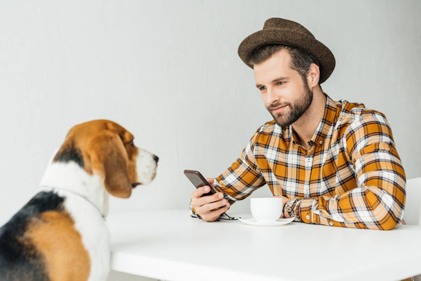 man sitting at table and looking at cute beagle - Valokuva, kuva