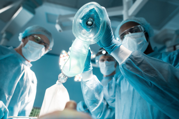 az afrikai-amerikai altatóorvos gazdaság oxigén maszk fölött, beteg, sebészet szobában Alulnézet - Fotó, kép