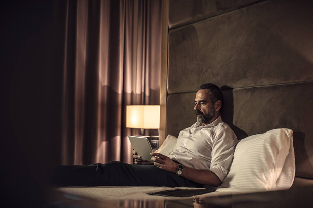 Businessman Relaxing on Bed - 写真・画像
