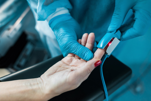 levágott kép visel pulzoximéter beteg ujját a műtő orvos - Fotó, kép