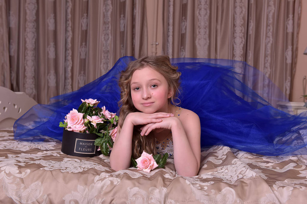 Young princess in a blue evening dress with roses - Fotó, kép