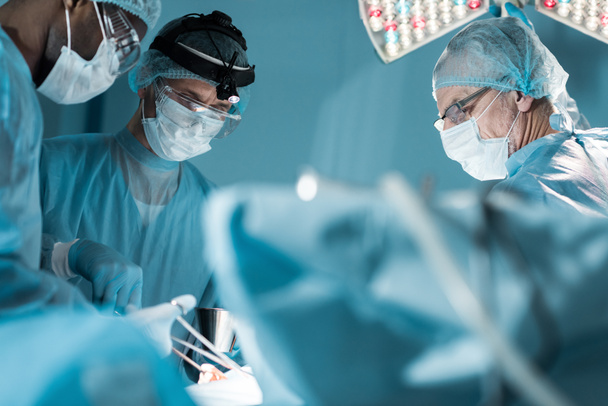 chirurghi multiculturali in maschere mediche operatorio paziente in sala operatoria
 - Foto, immagini