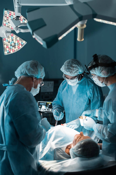 multi-etnisch chirurgen opereren patiënt in operatiekamer - Foto, afbeelding
