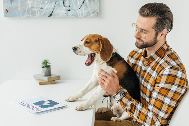 businessman holding yawning dog at table - Foto, imagen