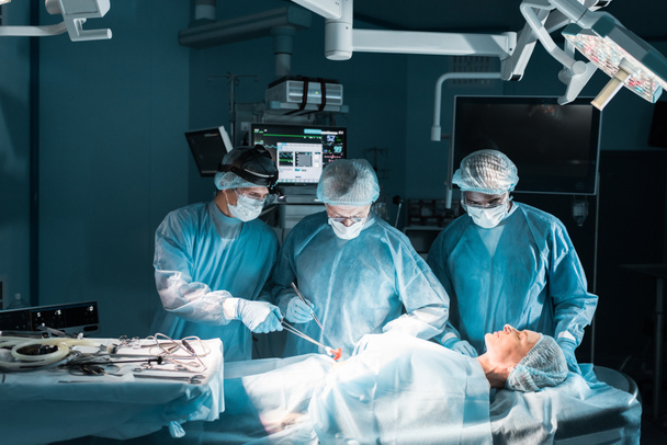 cirujanos multiculturales y paciente durante la cirugía
 - Foto, Imagen