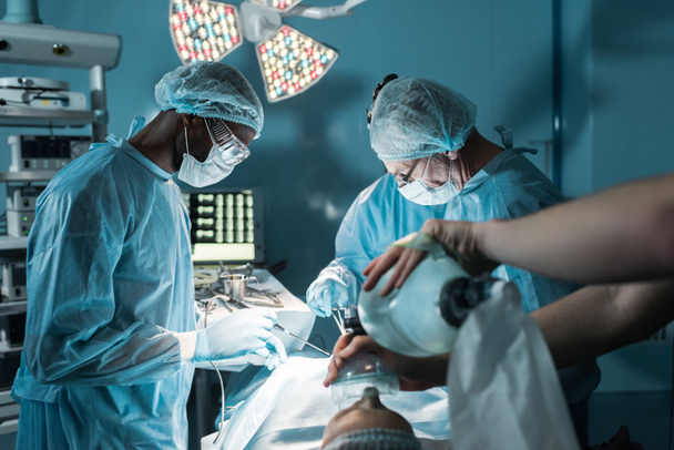 cirujanos multiétnicos y paciente en quirófano
 - Foto, Imagen