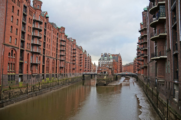 Speicherstadt. Hafenlager in Hamburg. Hamburg ist eine raue deutsche Stadt. die urbane Landschaft Norddeutschlands. Blick von der Brücke auf die Stadtkanäle. - Foto, Bild