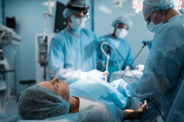 Cirujanos multiétnicos operando al paciente en quirófano
 - Foto, imagen