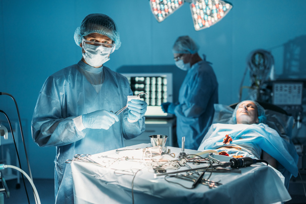 cirujano limpiando pinzas quirúrgicas y mirando la cámara en la sala de cirugía
 - Foto, imagen