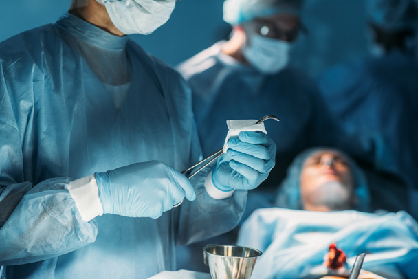 skadrowana chirurg czyszczenia pincety chirurgiczne w sali chirurgii - Zdjęcie, obraz