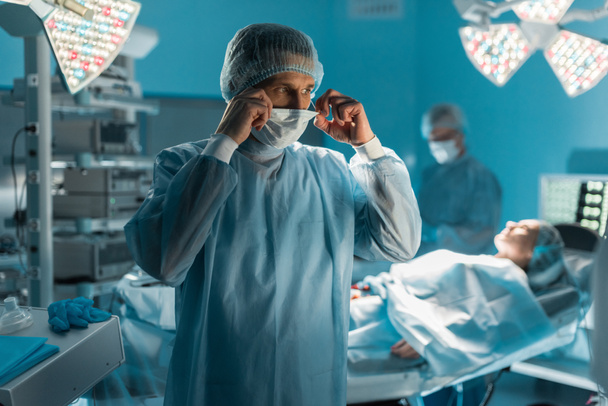 Chirurg trägt medizinische Maske im Operationssaal - Foto, Bild