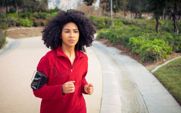 Beautiful athlete woman running with earphones, smart watch and  - Фото, зображення
