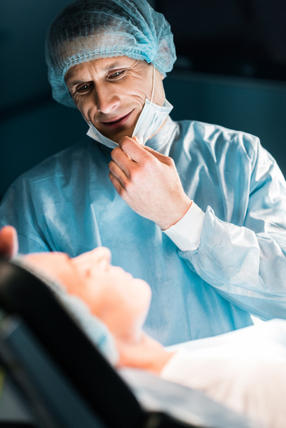 smiling doctor looking at patient in surgery room - Fotó, kép