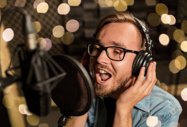 man with headphones singing at recording studio - Photo, image
