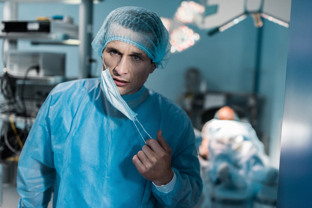 médecin enlever le masque médical dans la salle d'opération
 - Photo, image