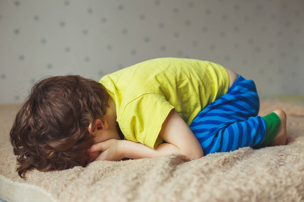 Tired toddler boy lying on the bed with his face down. Crying little kid - Foto, Bild