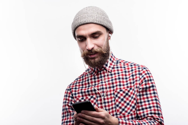 Bearded man in a beanie listening to music - Foto, afbeelding