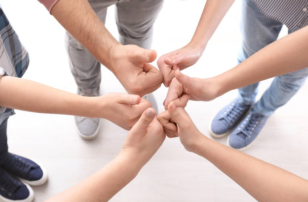 Jovens de pé em círculo e mostrando gesto de polegar para cima como símbolo de unidade
 - Foto, Imagem