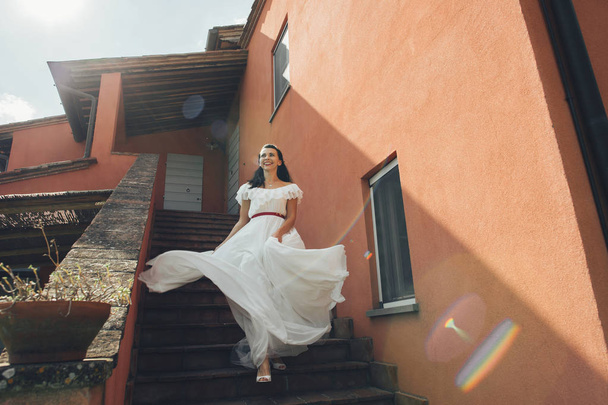 Bride coming down on stairs in sunny day - Фото, зображення