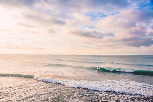 サーファーの日没で完璧な海の波に乗って。冬の水着でサーフィン   - 写真・画像