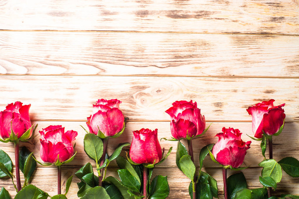 Czerwony kwiat róży na drewnianym stole.  - Zdjęcie, obraz