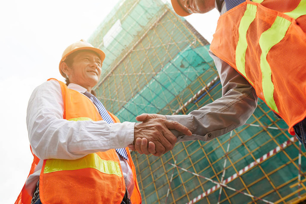 Wietnamski-inżynier i drżenie rąk placu budowy wykonawca - Zdjęcie, obraz