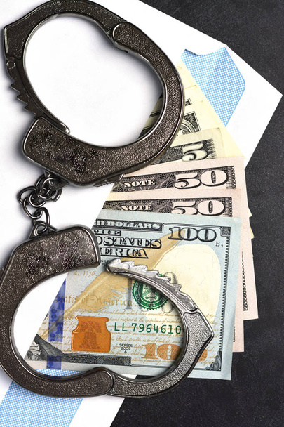 Omkoping en corruptie concept met handboeien op envelop vol geld - Foto, afbeelding