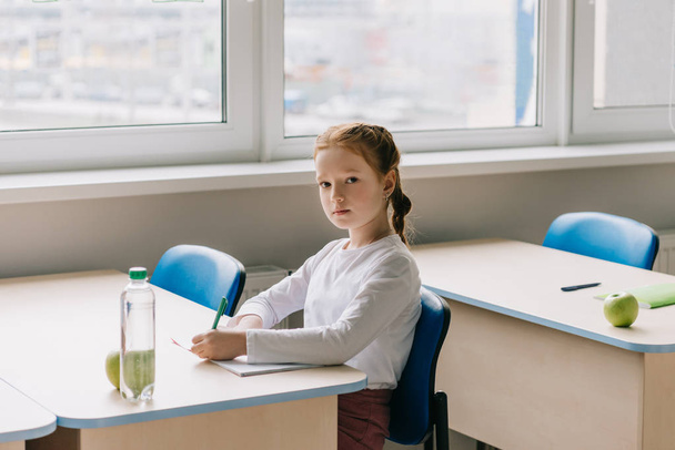 belle petite écolière écrivant en classe à l'école
 - Photo, image