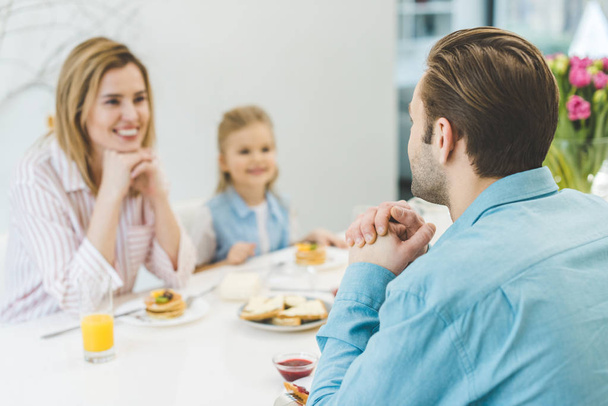 focus selettivo dell'uomo che fa colazione con la famiglia a casa
 - Foto, immagini