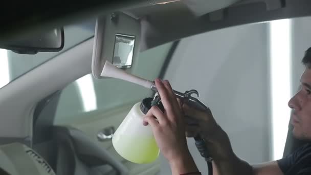Autó-service. Munkavállaló által egy speciális tisztítószerek, nyomás alatt belső mosás. - Felvétel, videó