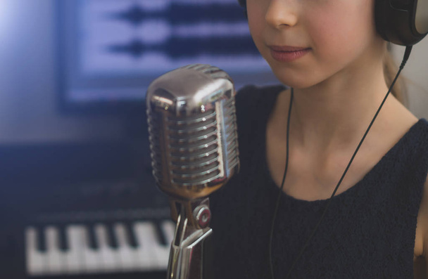 Niña cantando una canción en el estudio de grabación en casa
. - Foto, Imagen