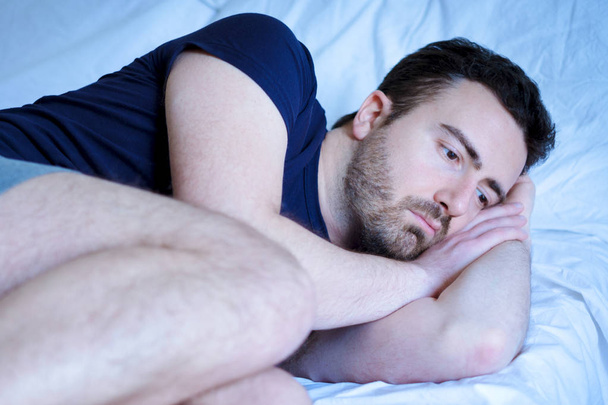 Sad and upset man trying to sleep in bed - Photo, Image