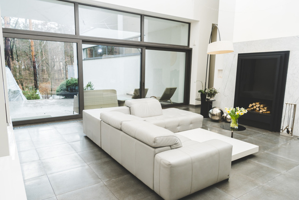 weergave van lege woonkamer met witte Bank en boeket bloemen op salontafel - Foto, afbeelding